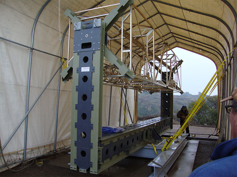The low dielectric antenna test fixture on location in an outdoor setting underneath a tent structure. It is holding up a cage structure that has yet to be loaded.